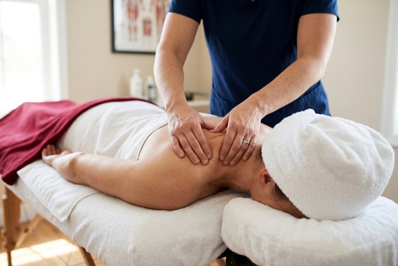 Therapist performing myofascial release on a patient's shoulder and upper back